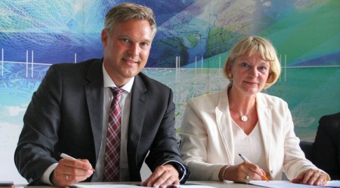 Präsident Wolfgang Bauer und die Präsidentin der OTH Amberg-Weiden Prof. Dr. Andrea Klug lächeln in die Kamera und halten jeweils einen Stift in der Hand.